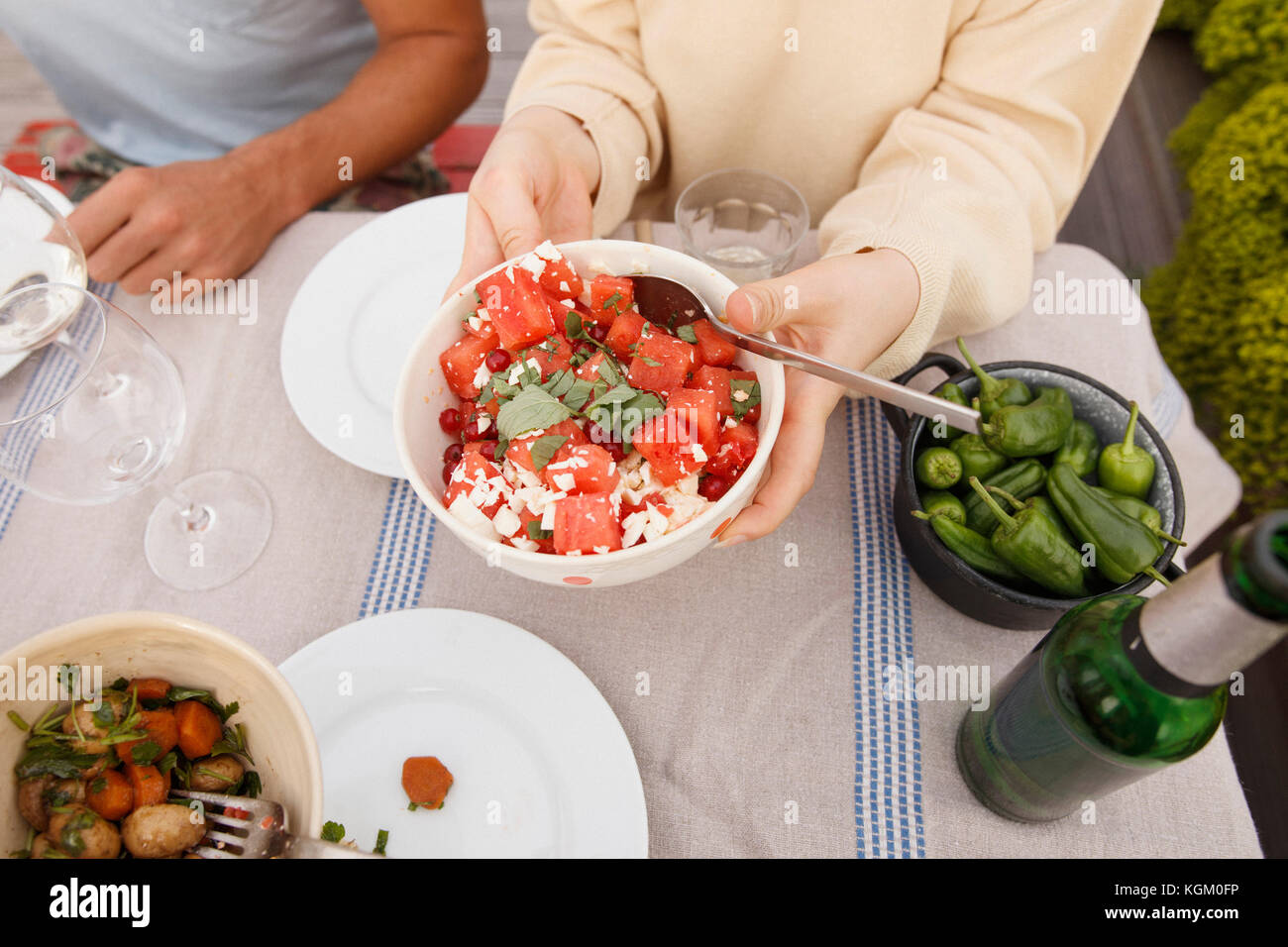 Elevato angolo di visione della donna azienda insalata di frutta coppa a tavolo esterno mentre è seduto con un amico Foto Stock