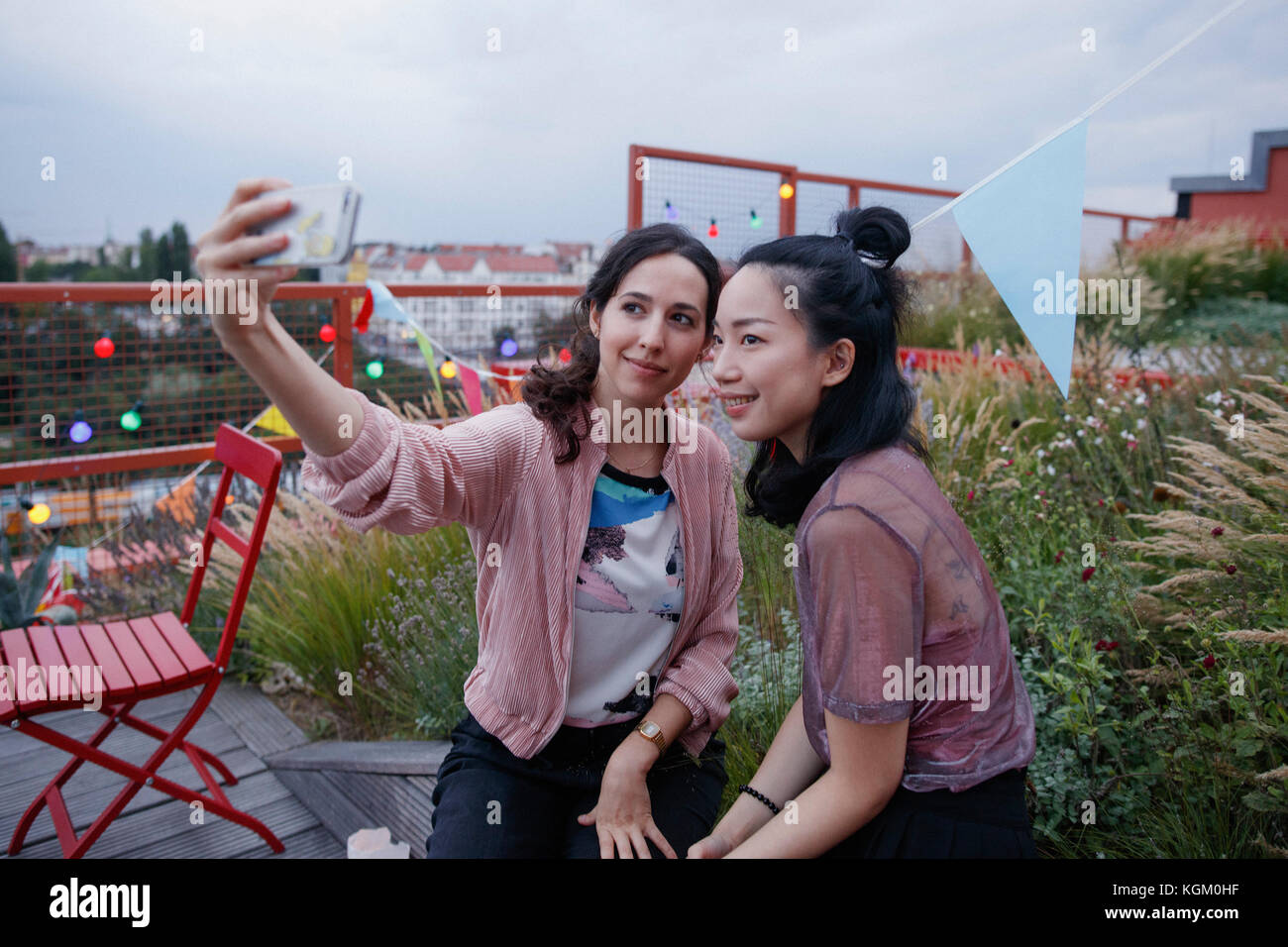 Donna sorridente tenendo selfie con smart phone sul patio Foto Stock