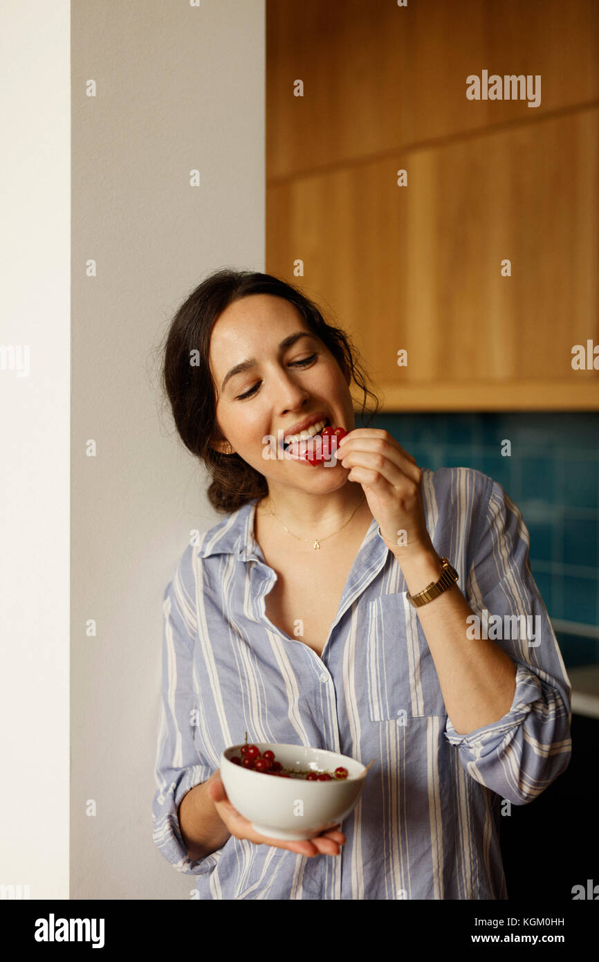 Giovane donna mangiare ribes rosso a casa Foto Stock