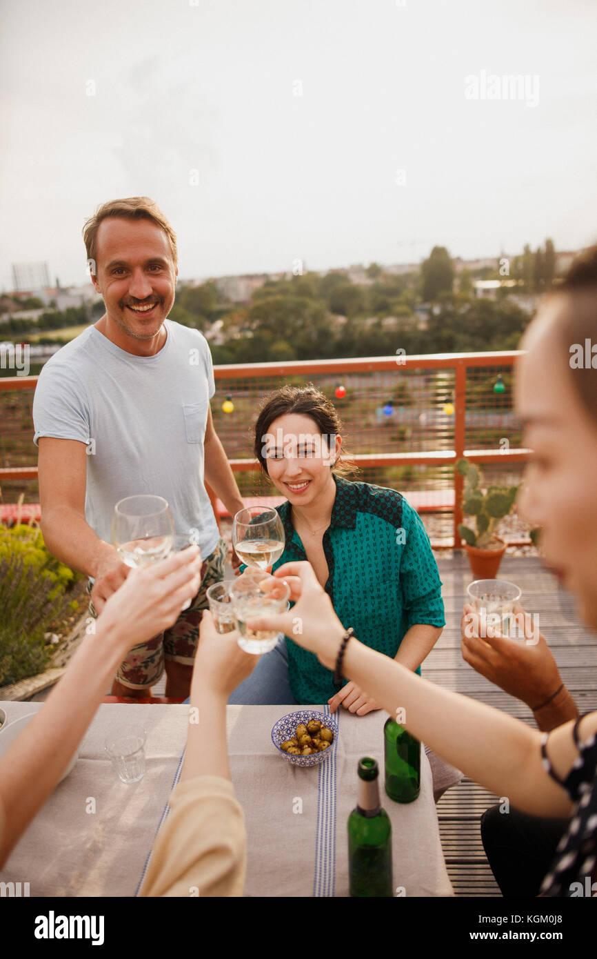 Happy amici wineglasses tostatura al tavolo esterno sul patio Foto Stock