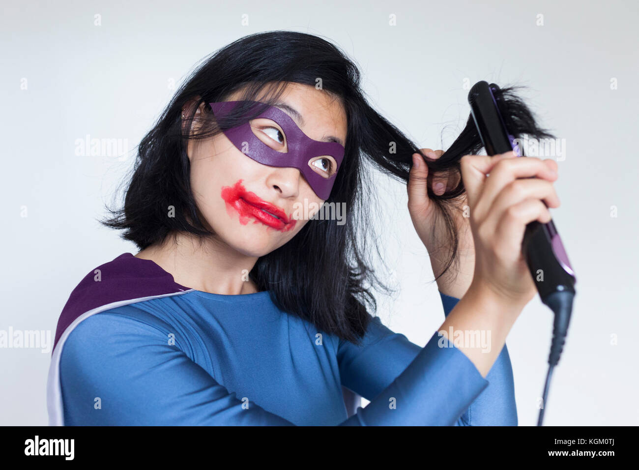 Il supereroe femminile con sbavature del rossetto capelli dritti contro uno sfondo grigio Foto Stock