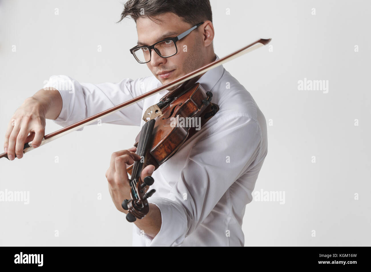Fiducioso giovane uomo suona il violino contro uno sfondo bianco Foto Stock