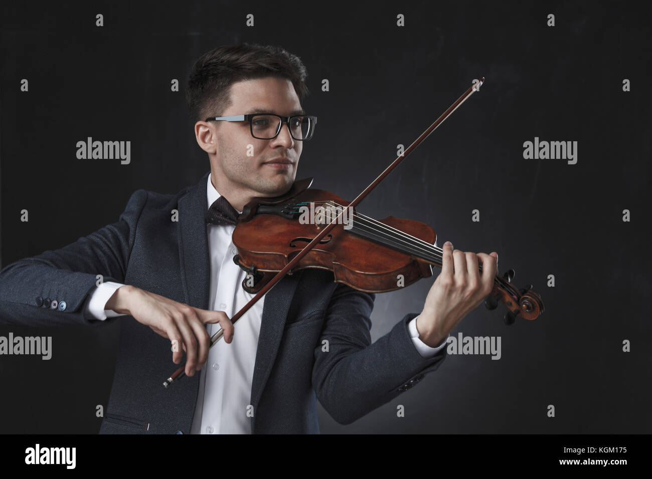 Sorridente bello il violinista suona il violino su sfondo nero Foto Stock