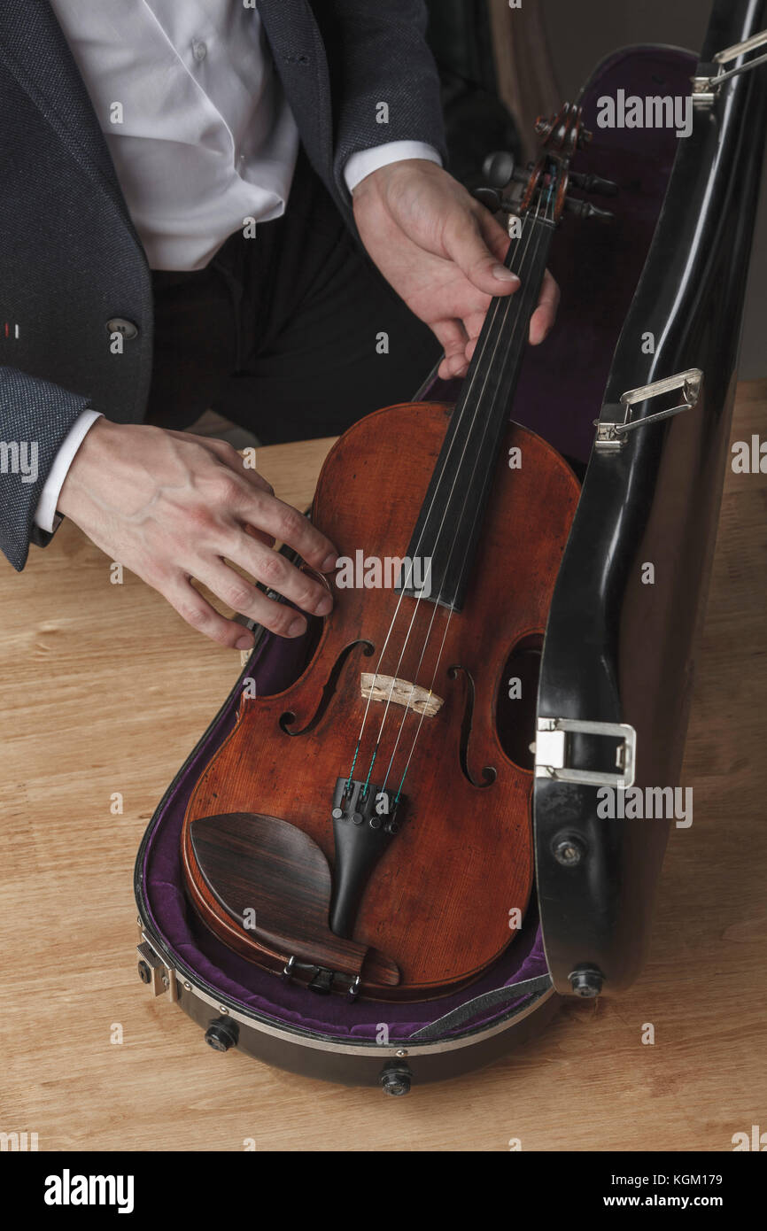 Sezione mediana dell'uomo mantenendo il violino nel caso a tavola Foto Stock