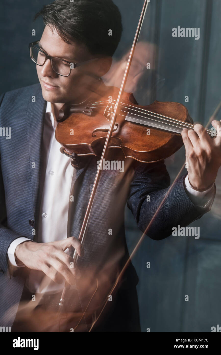 Moto sfocata del bel giovane suona il violino con gli occhi chiusi Foto Stock