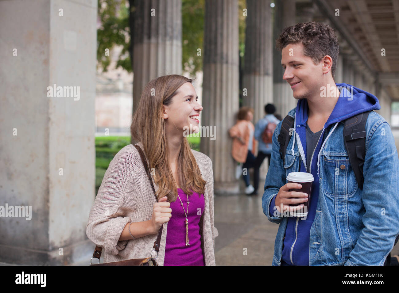 Sorridente giovani amici di parlare mentre in piedi contro le colonne Foto Stock