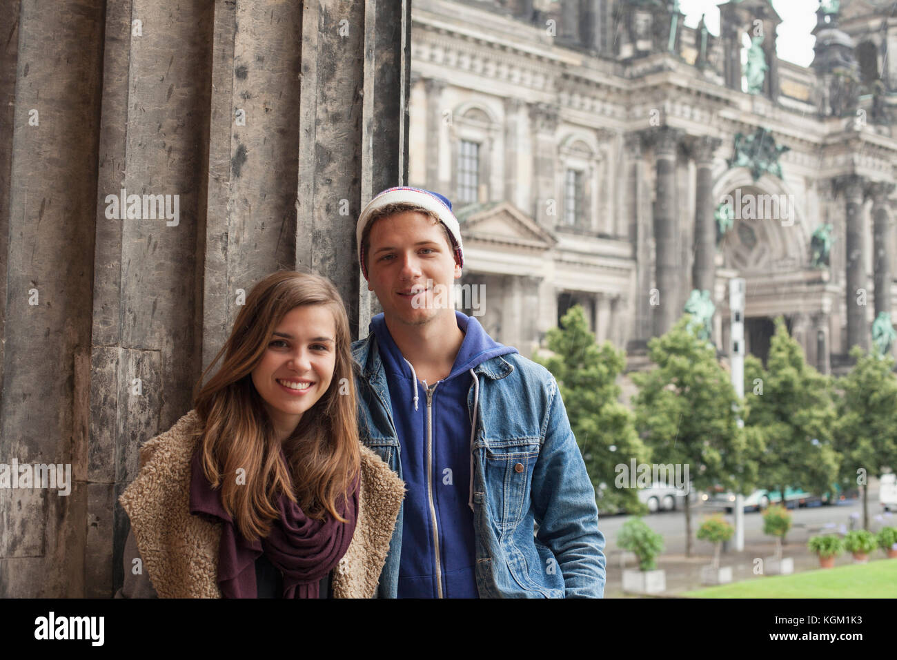 Ritratto di sorridere giovani amici in piedi dalla colonna ad Altes Museum contro la Cattedrale di Berlino Foto Stock