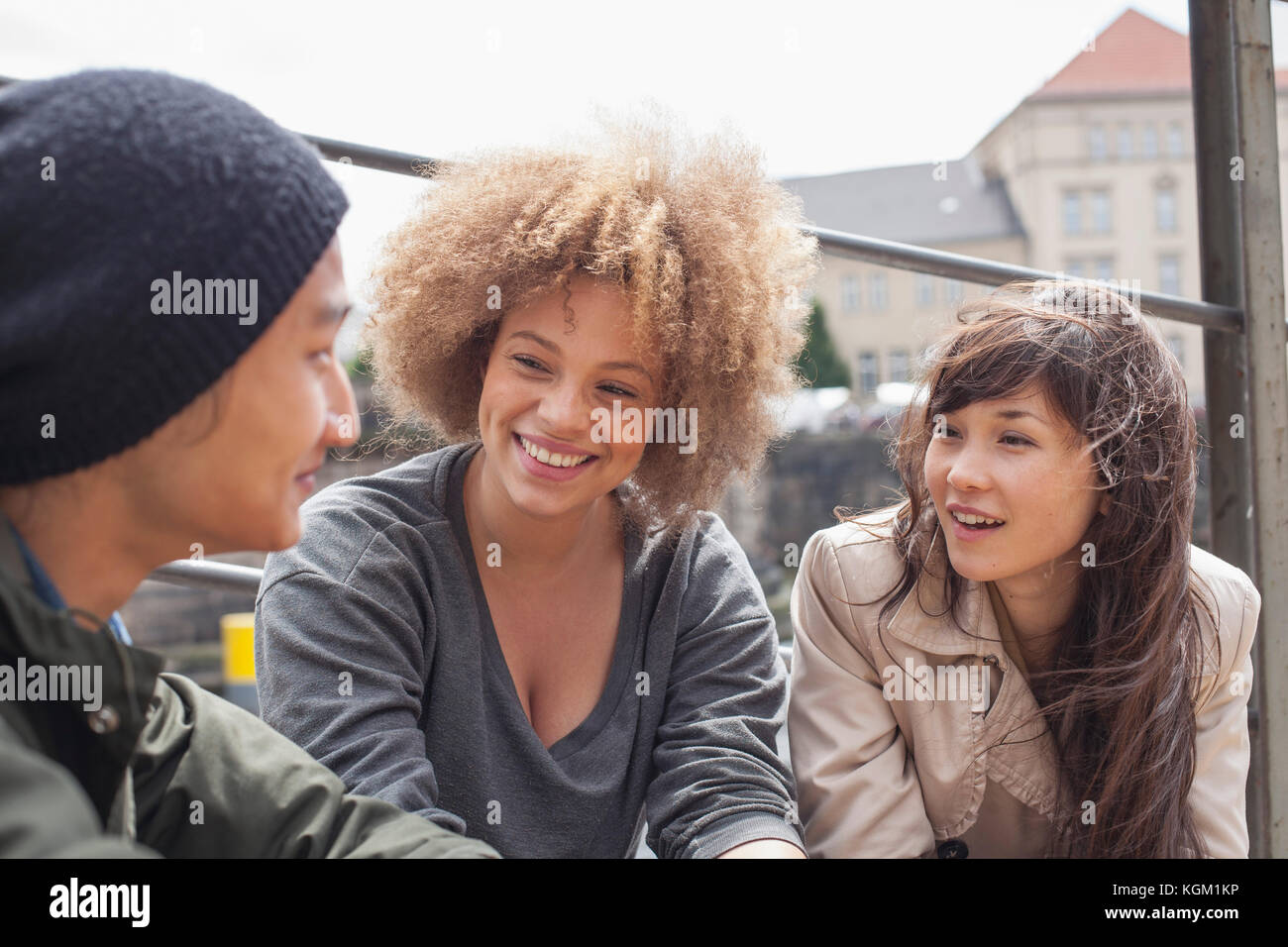 Sorridente giovani amici parlano seduti sulla giornata di sole Foto Stock