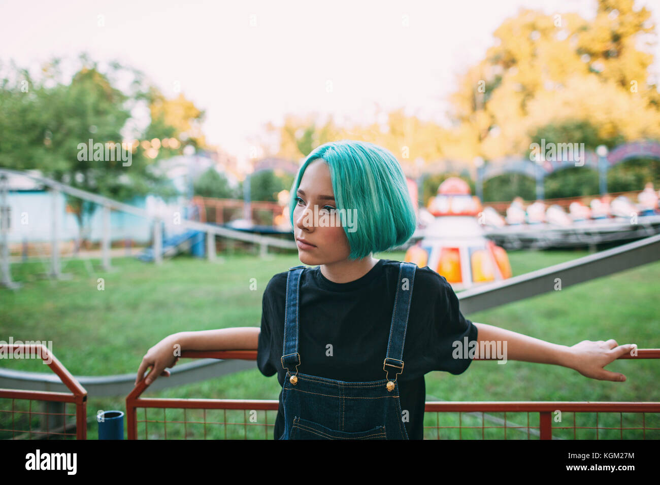 Premurosa ragazza adolescente in piedi dalla ringhiera presso il parco di divertimenti Foto Stock