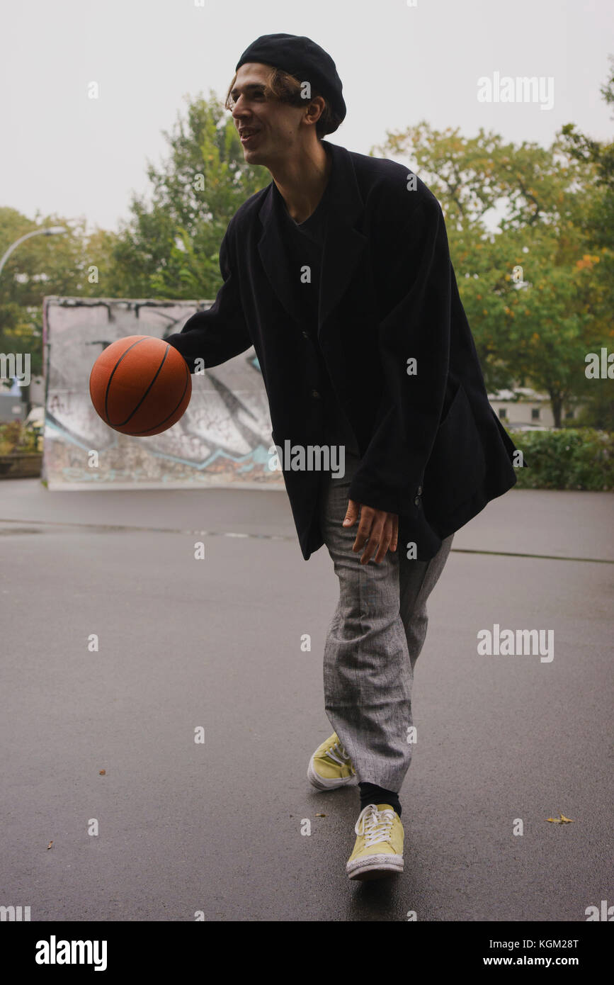 Giovane uomo giocare a basket in posizione di parcheggio Foto Stock