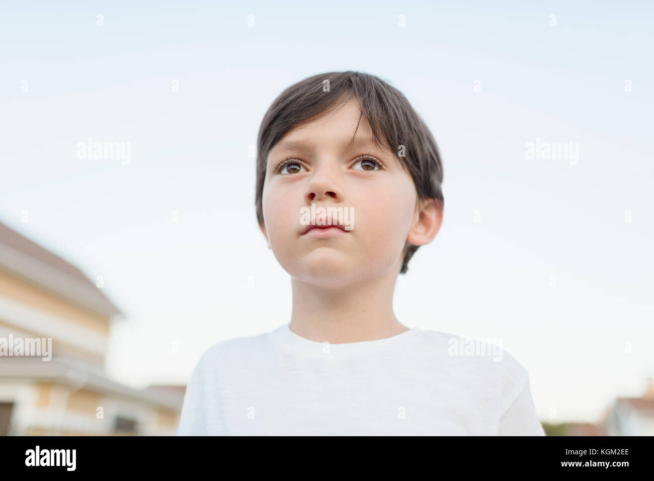 Close-up del ragazzo che guarda lontano mentre in piedi contro il cielo chiaro Foto Stock