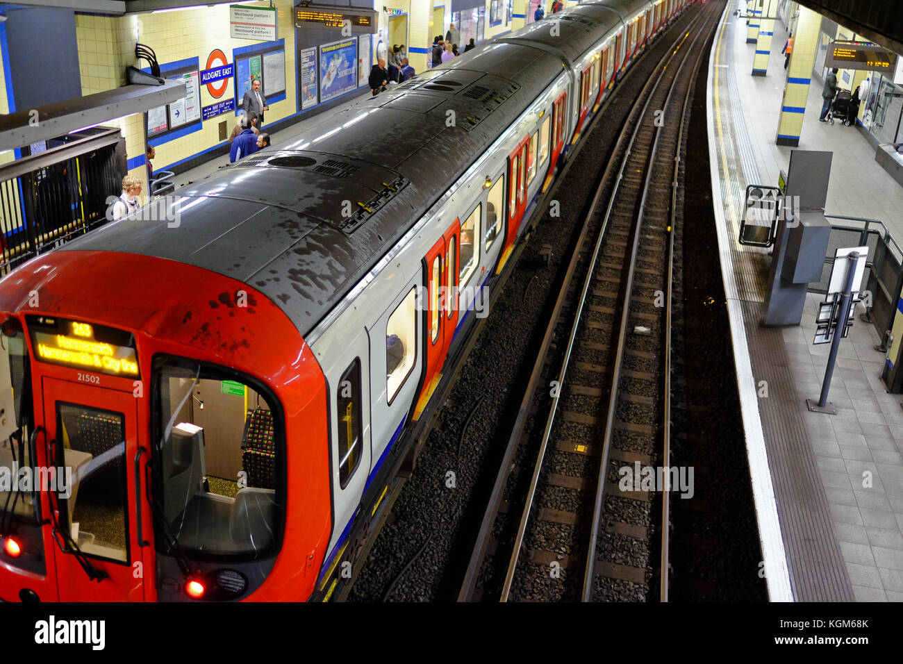 Un treno della metropolitana presso la piattaforma della stazione di Aldgate East sulla metropolitana di Londra con i pendolari in attesa Foto Stock