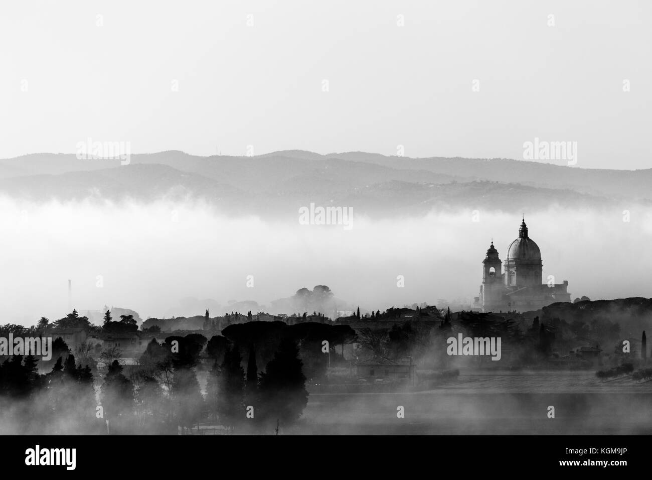 Vista su Santa Maria degli Angeli chiesa papale (Assisi) contro uno sfondo di nebbia all'alba Foto Stock