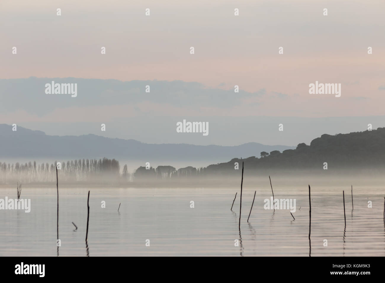 Un lago al tramonto, con bellissime tonalità calde nel cielo e acqua e un'isola nel mezzo della nebbia Foto Stock
