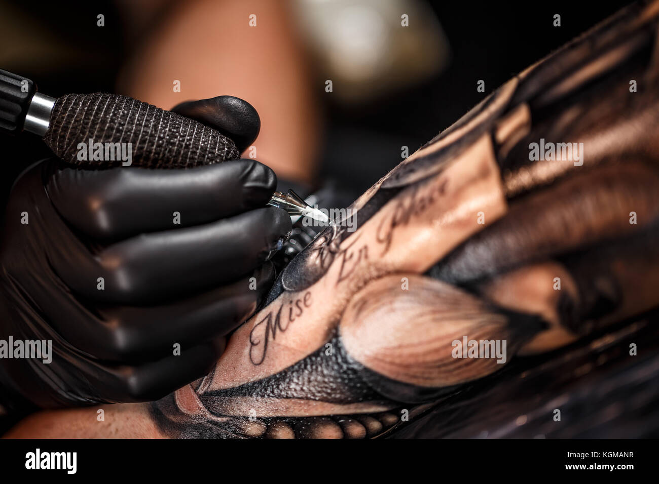 Un professional tattoo artist introduce l'inchiostro nero in pelle utilizzando un ago da un dermografo. Foto Stock