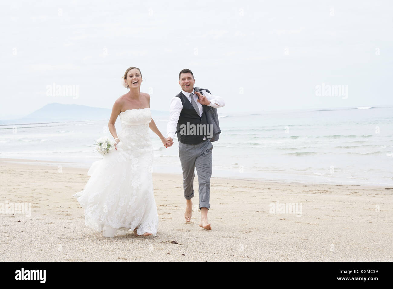 Allegro appena una coppia sposata in esecuzione su di una spiaggia di sabbia Foto Stock