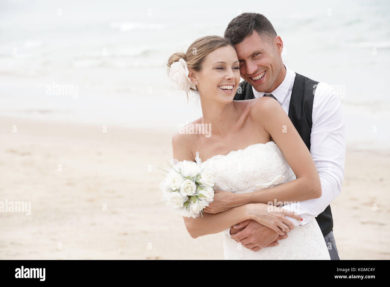 Ritratto di felice sposa e lo sposo che abbraccia ogni altro in spiaggia Foto Stock