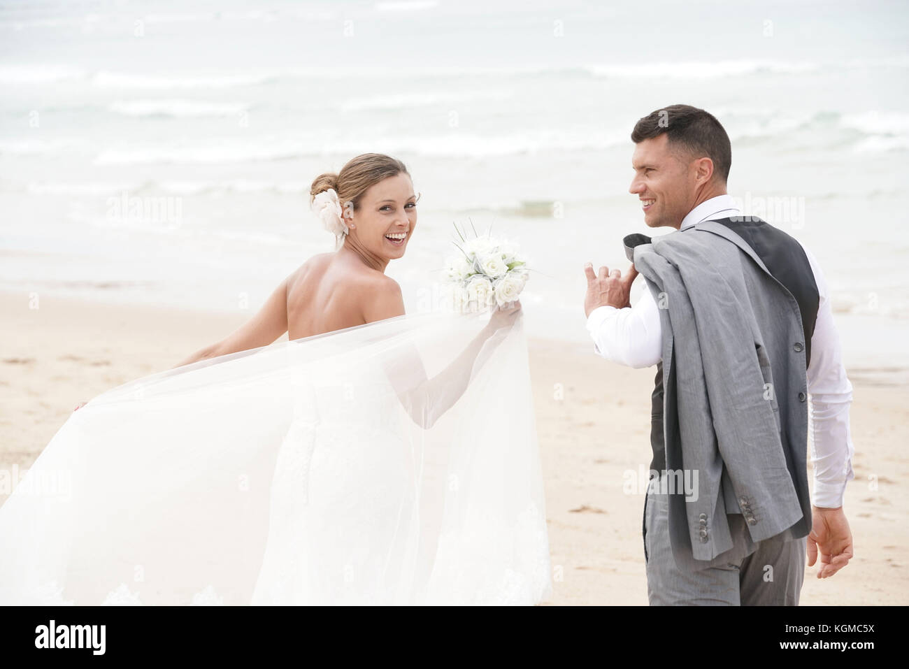 Allegro appena sposato giovane di camminare sulla spiaggia Foto Stock
