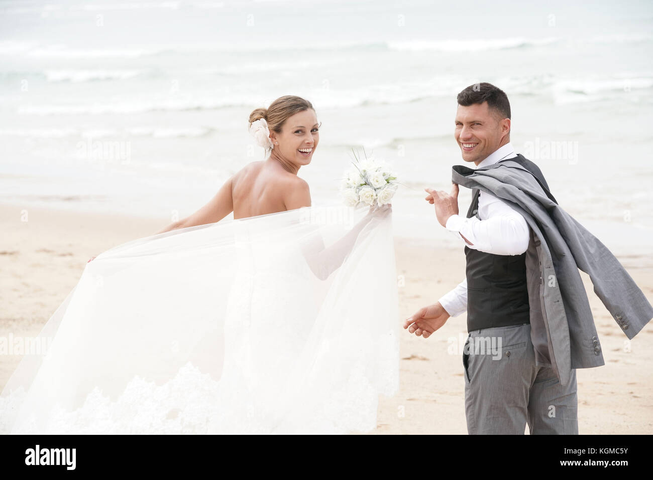 Allegro appena sposato giovane di camminare sulla spiaggia Foto Stock