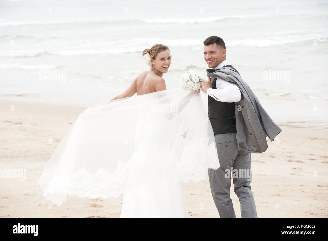 Allegro appena sposato giovane di camminare sulla spiaggia Foto Stock