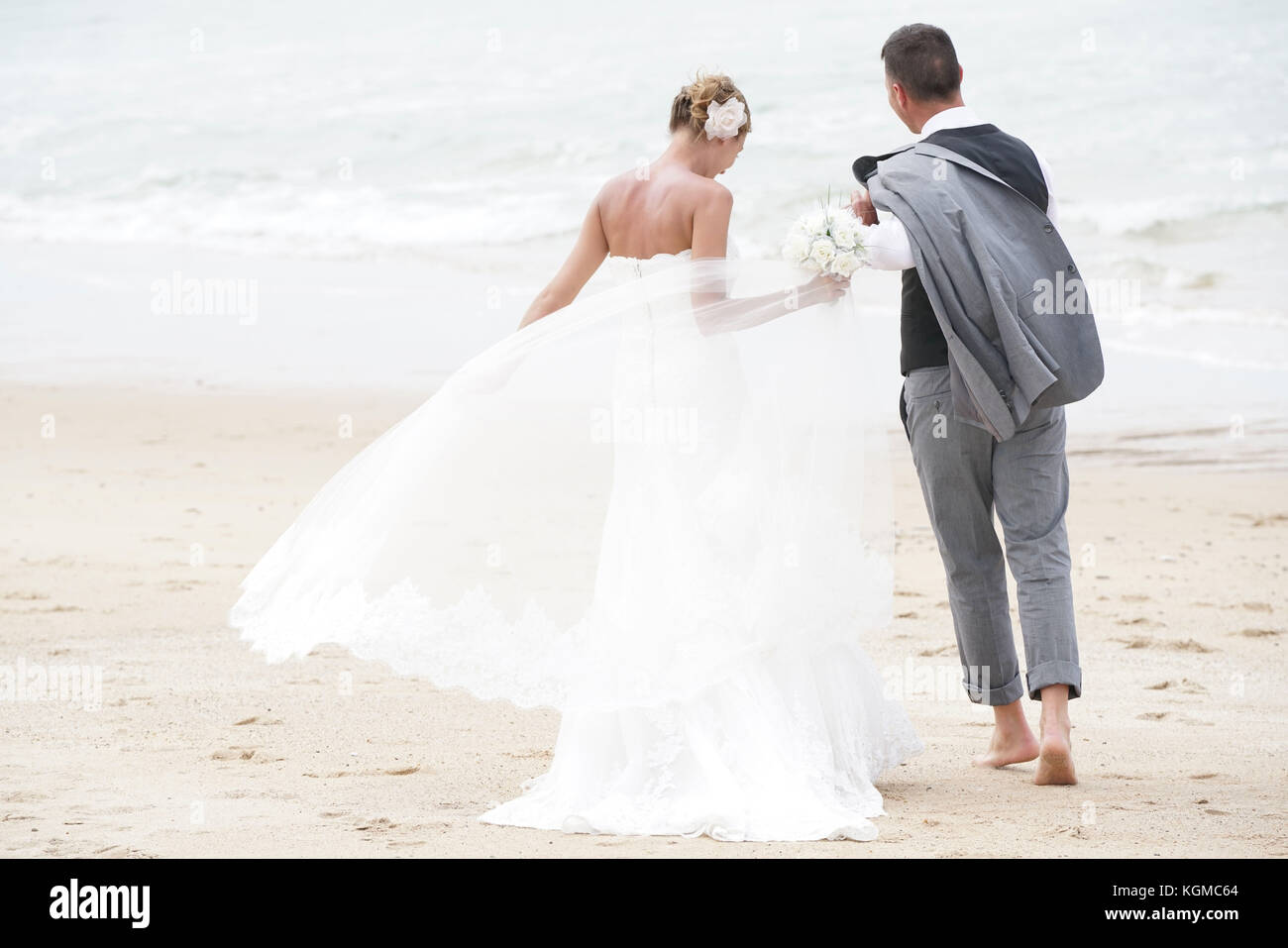 Allegro appena sposato giovane di camminare sulla spiaggia Foto Stock