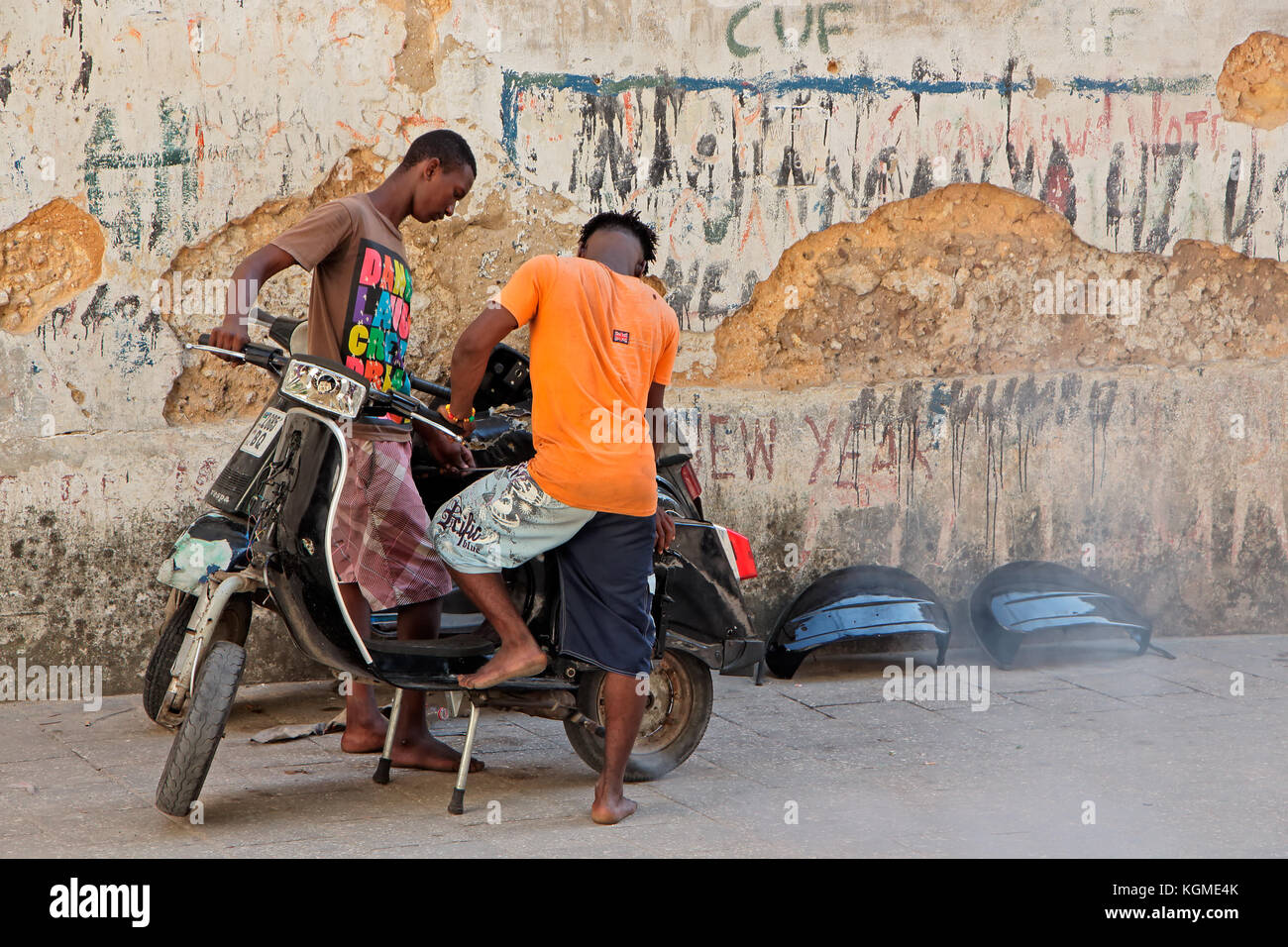 Stone Town zanzibar, Tanzania - ottobre 29, 2014: Uomini non identificati lavorando su uno scooter (moto) in uno stretto vicolo della storica città di pietra Foto Stock