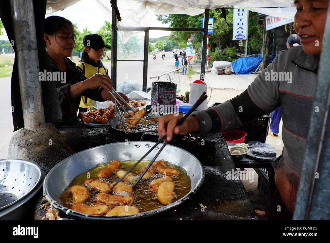 Binh Dinh, Viet Nam, vietnamita donna street food vendor guadagnare soldi da snack alimentare sulla strada, femmina asiatica Frittura di banane fritte su hawk, Vietnam Foto Stock