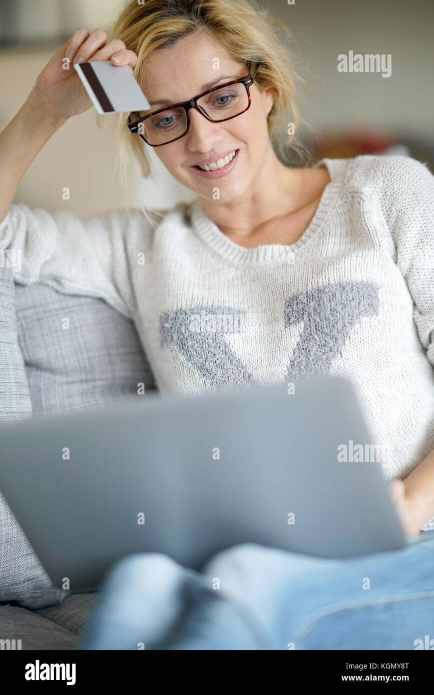Donna di mezza età a casa acquisti su internet con carta di credito Foto Stock