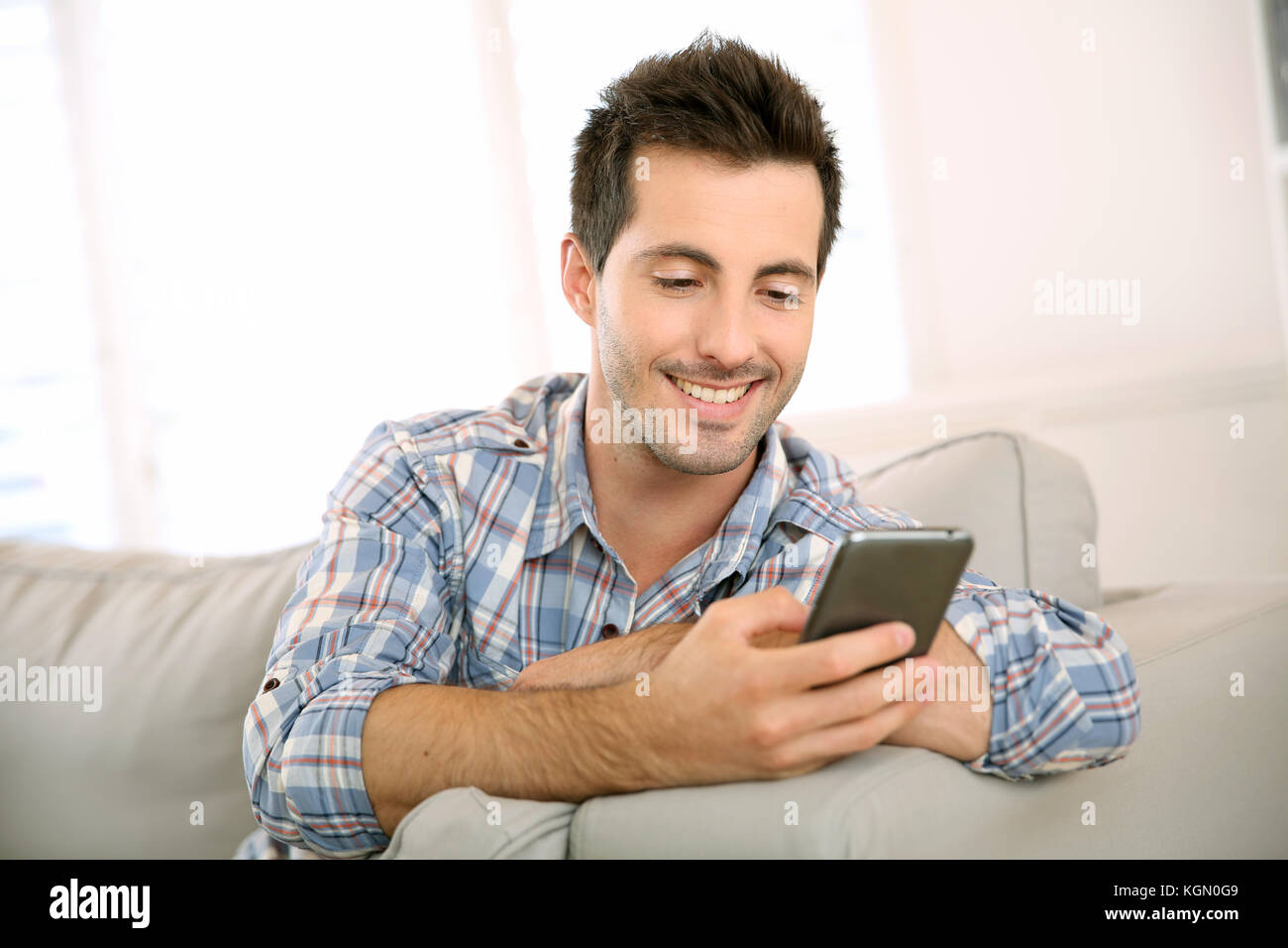 Bel uomo utilizza lo smartphone a casa Foto Stock