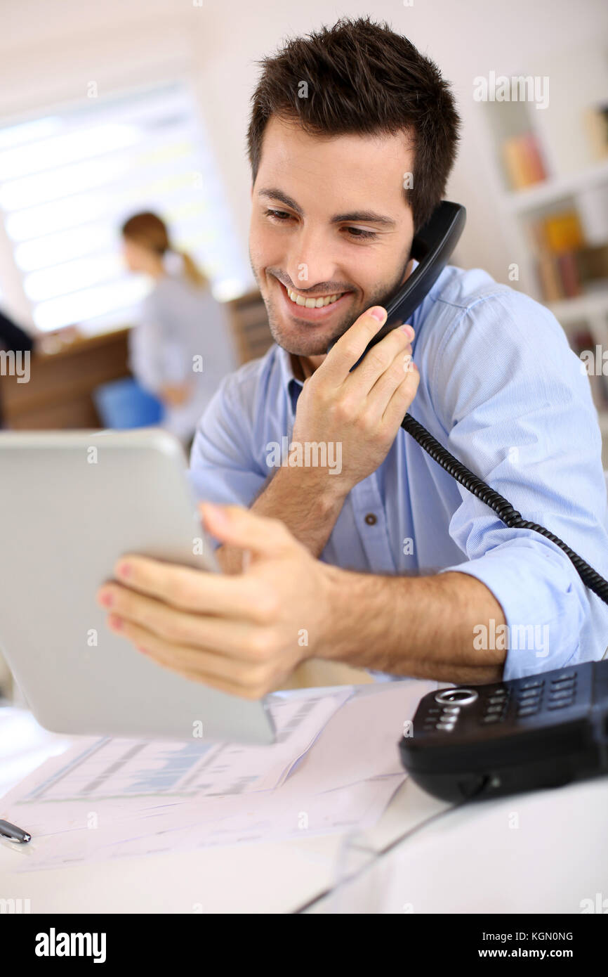 Uomo sorridente in ufficio a rispondere al telefono Foto stock - Alamy