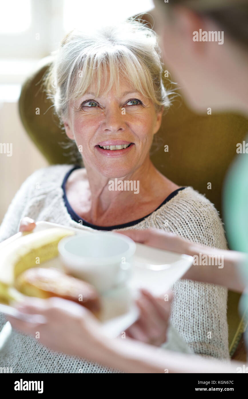 Infermiere portando la colazione per senior paziente femmina Foto Stock