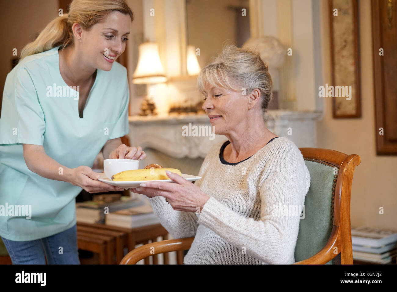 Infermiere portando la colazione per senior paziente femmina Foto Stock