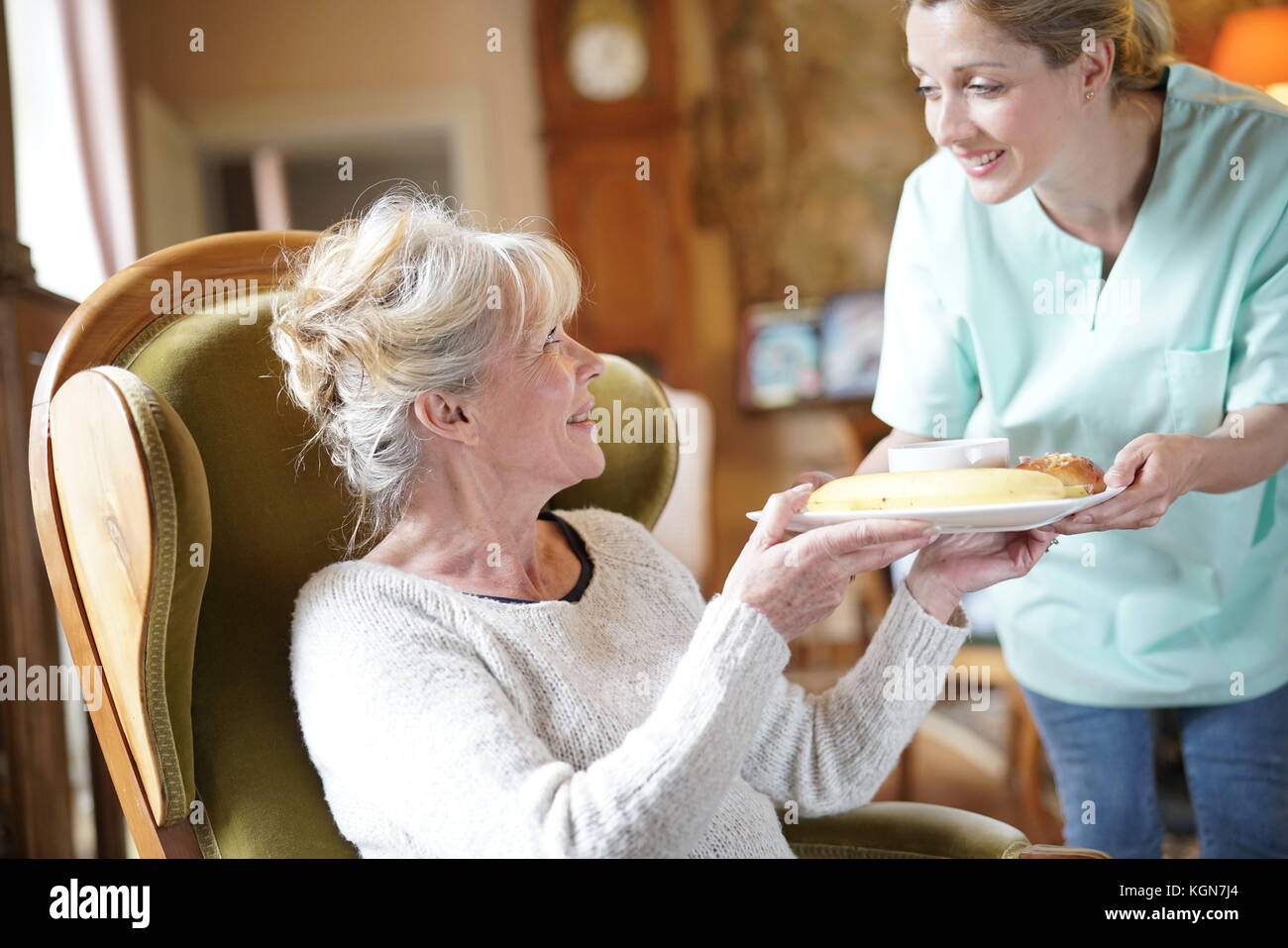 Infermiere portando la colazione per senior paziente femmina Foto Stock