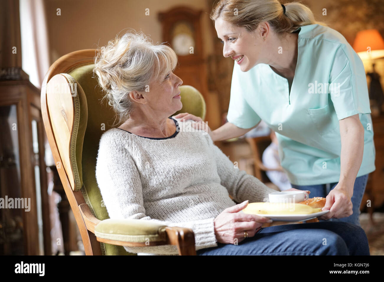 Infermiere portando la colazione per senior paziente femmina Foto Stock