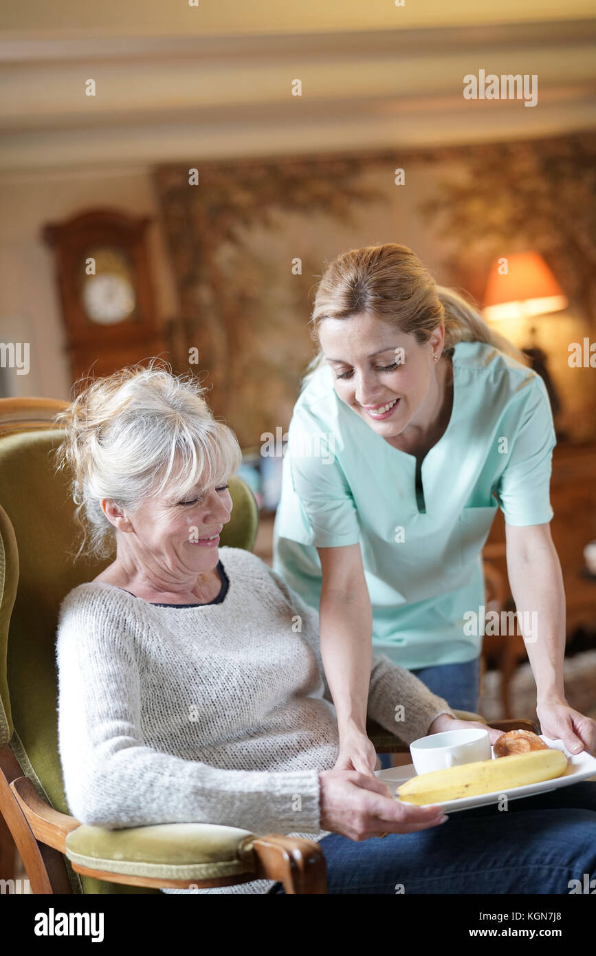 Infermiere portando la colazione per senior paziente femmina Foto Stock