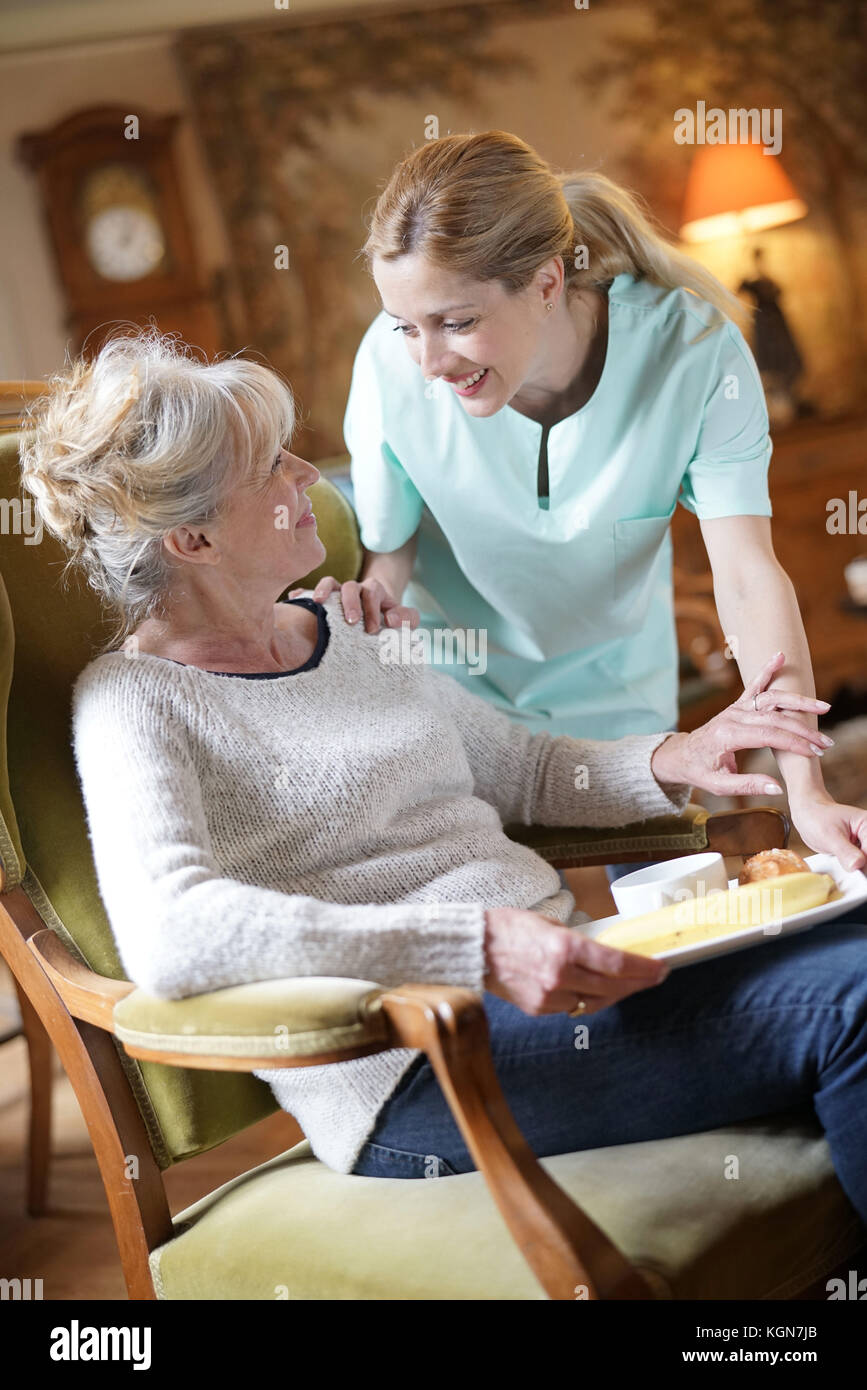 Infermiere portando la colazione per senior paziente femmina Foto Stock
