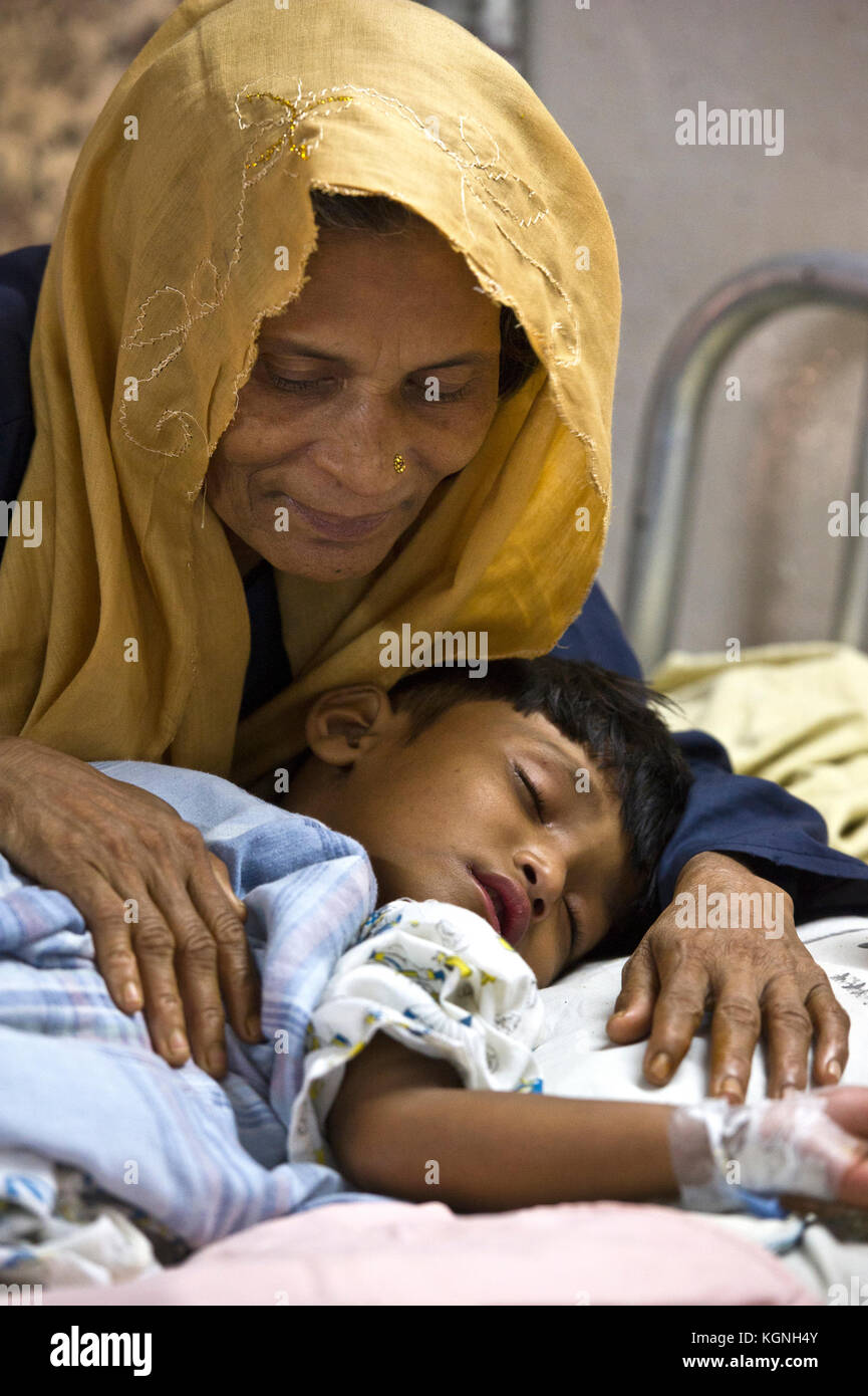 Una nonna Rohingya conforta la sua nipote addormentata mentre viene curata alla nuova unità di cura Rohingya del Memorial Christian Hospital di Malumghat, Bangladesh. Molti dei rifugiati in arrivo stanno mostrando un'ampia gamma di ferite causate da colpi di arma da fuoco, arti spezzate da cadute traumatiche in fuga, incidenti stradali e altri disturbi acquiacei durante il loro lungo viaggio dal Myanmar. (ALAMY LIVE NEWS/Chuck Bigger/9 novembre 2017) Foto Stock