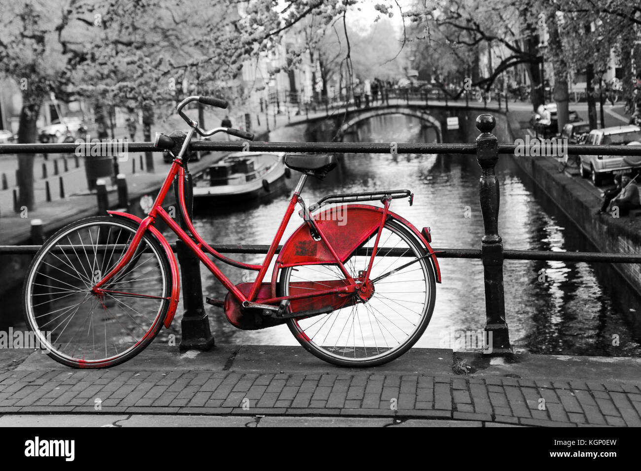 Una foto di un solitario red bici sul ponte sul canale di Amsterdam. Lo sfondo è bianco e nero. Foto Stock