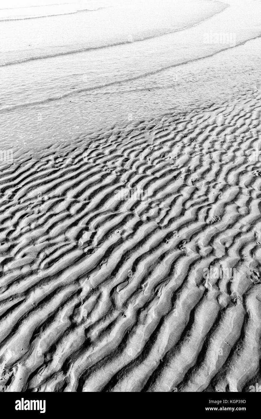 Immagine in bianco e nero della linea costiera inferiore increspata quando le prime increspature della marea in arrivo avanzano. Creste fluviali per studio di stratigrafia. Foto Stock