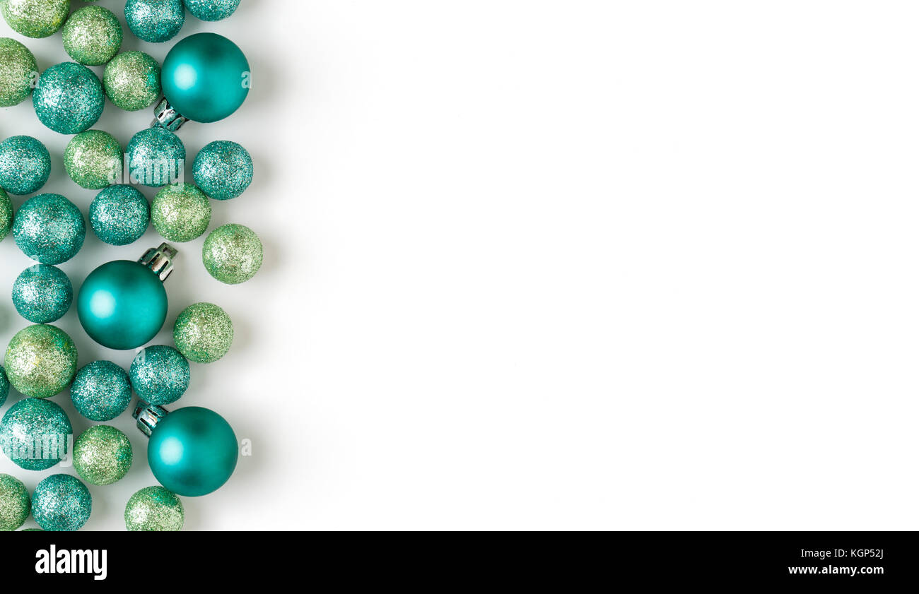 Bella, luminosa, moderna, il blu e il verde per le vacanze di Natale ornamenti decorazioni con scintillanti glitter su sfondo bianco. Orizzontale sinistro confine. Foto Stock