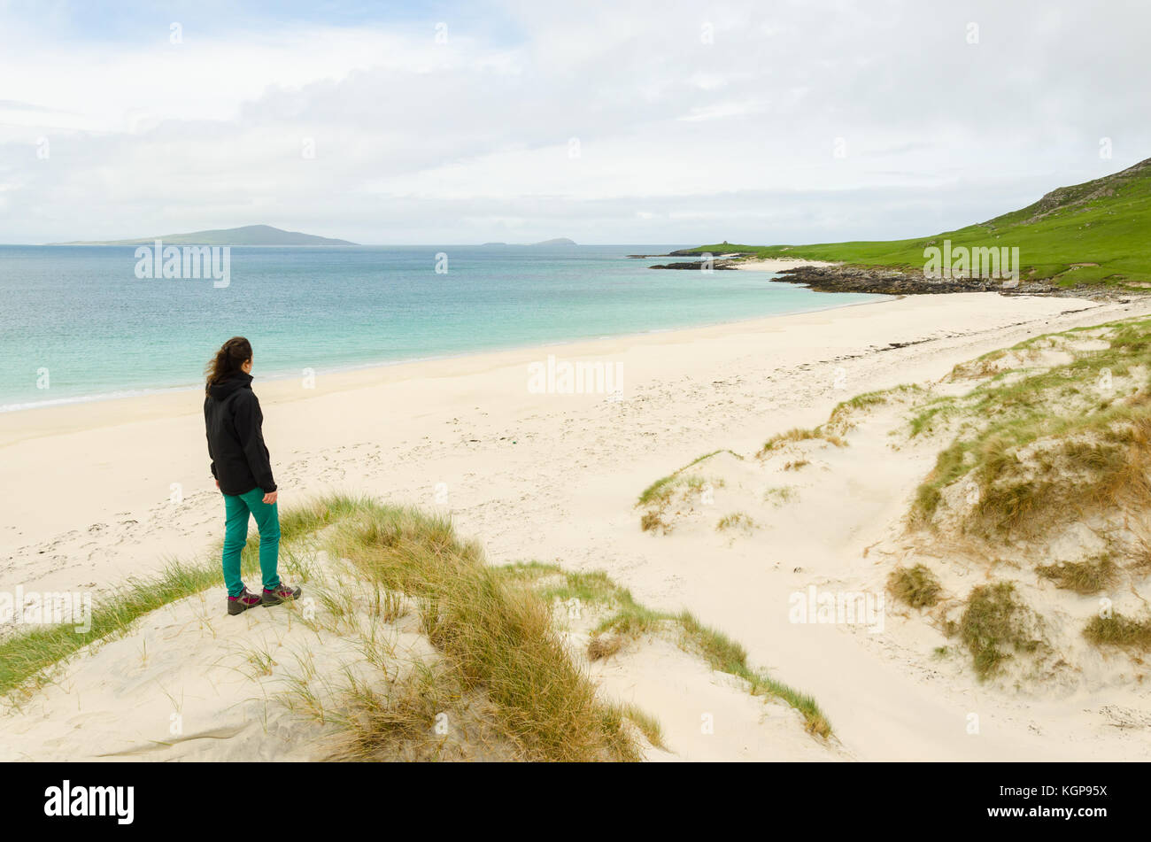 Giovane donna da dietro ammirando un vuoto di spiaggia di sabbia bianca nelle Ebridi Esterne, Scozia uk. Foto Stock