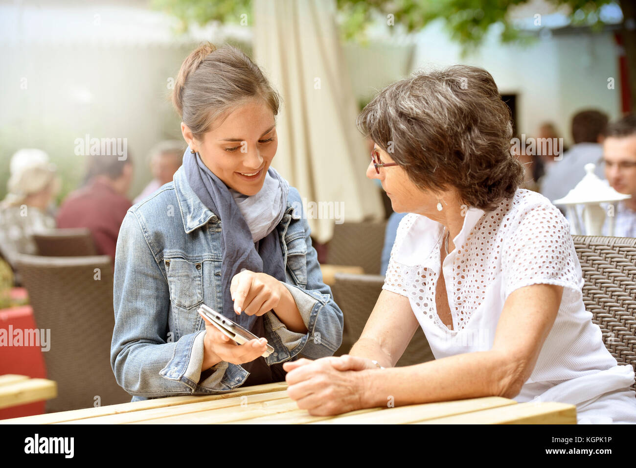 Donna anziana e accompagnatore a casa nella terrazza del caffè con smartphone Foto Stock
