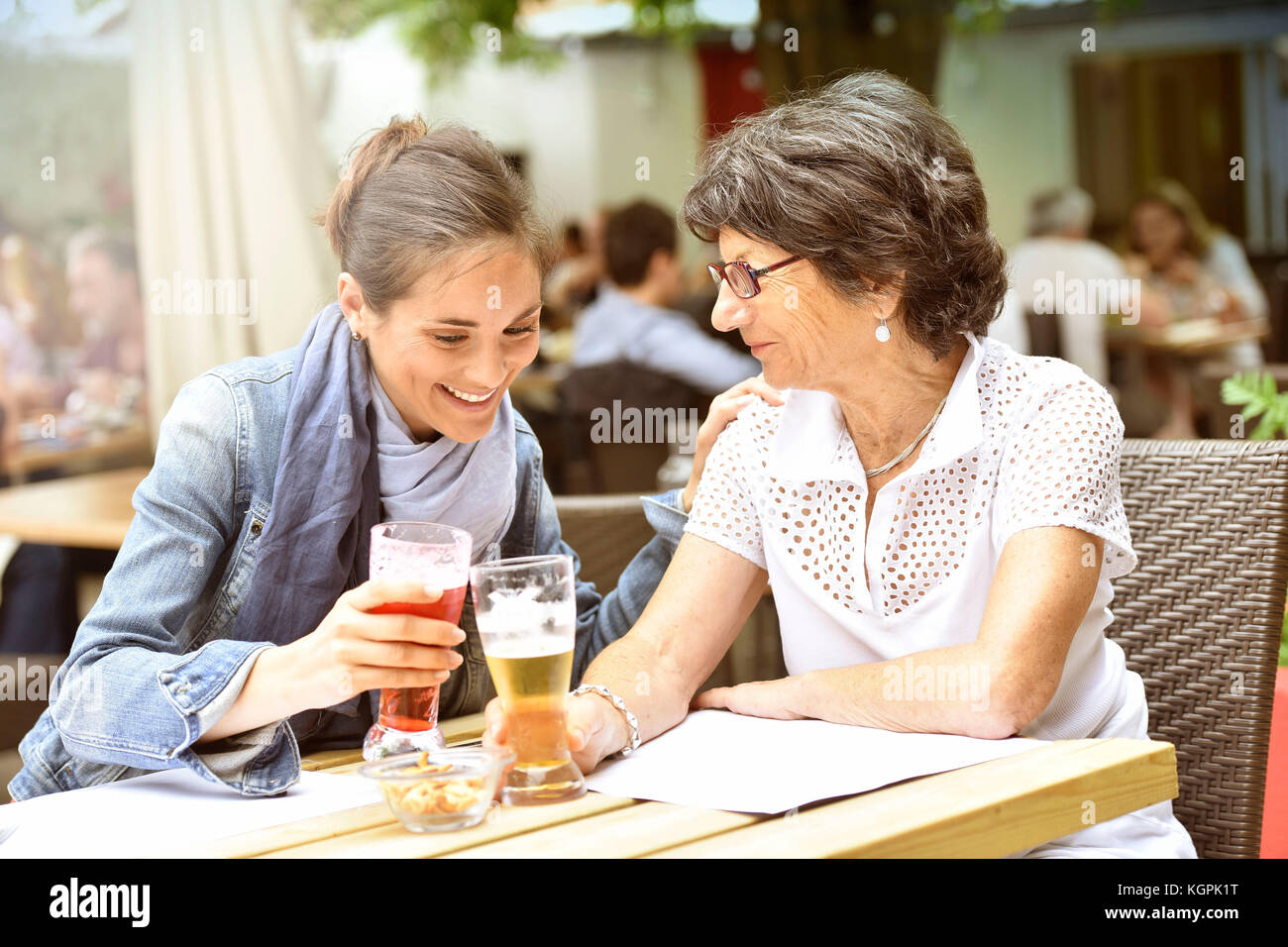 Donna anziana e accompagnatore a casa nella terrazza del caffè con smartphone Foto Stock