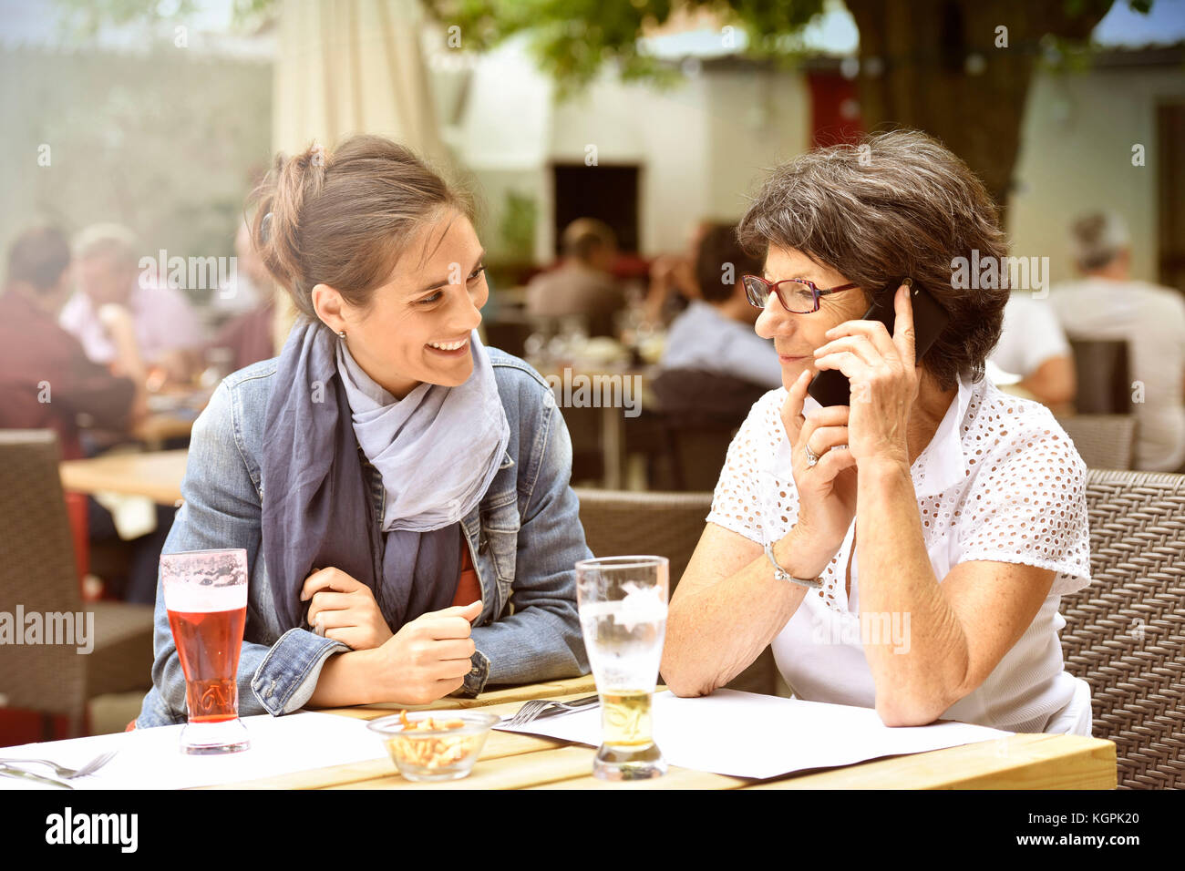 Donna anziana e accompagnatore a casa nella terrazza del caffè con smartphone Foto Stock
