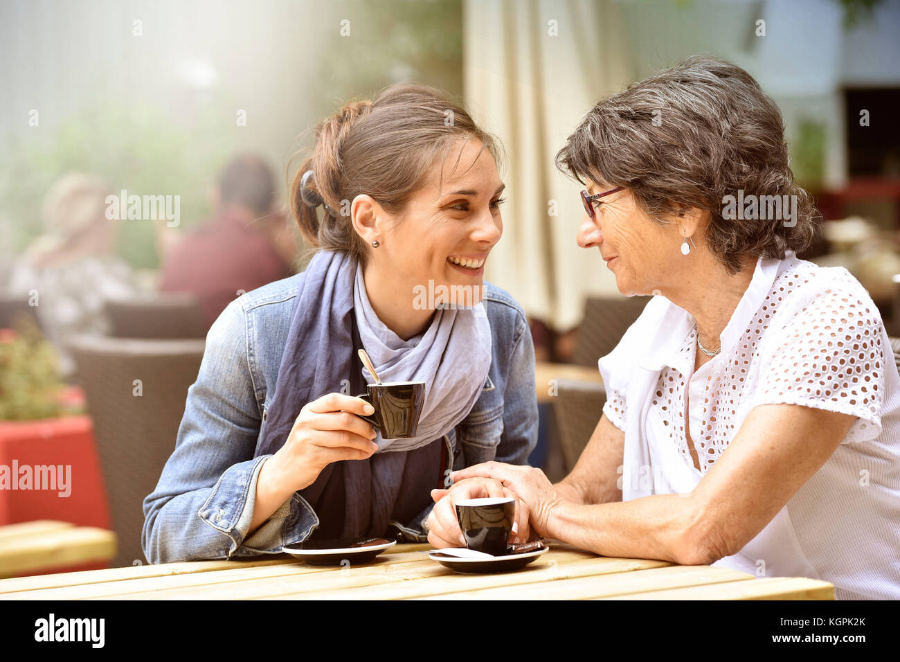 Donna anziana con accompagnatore a casa che ha il caffè insieme Foto Stock