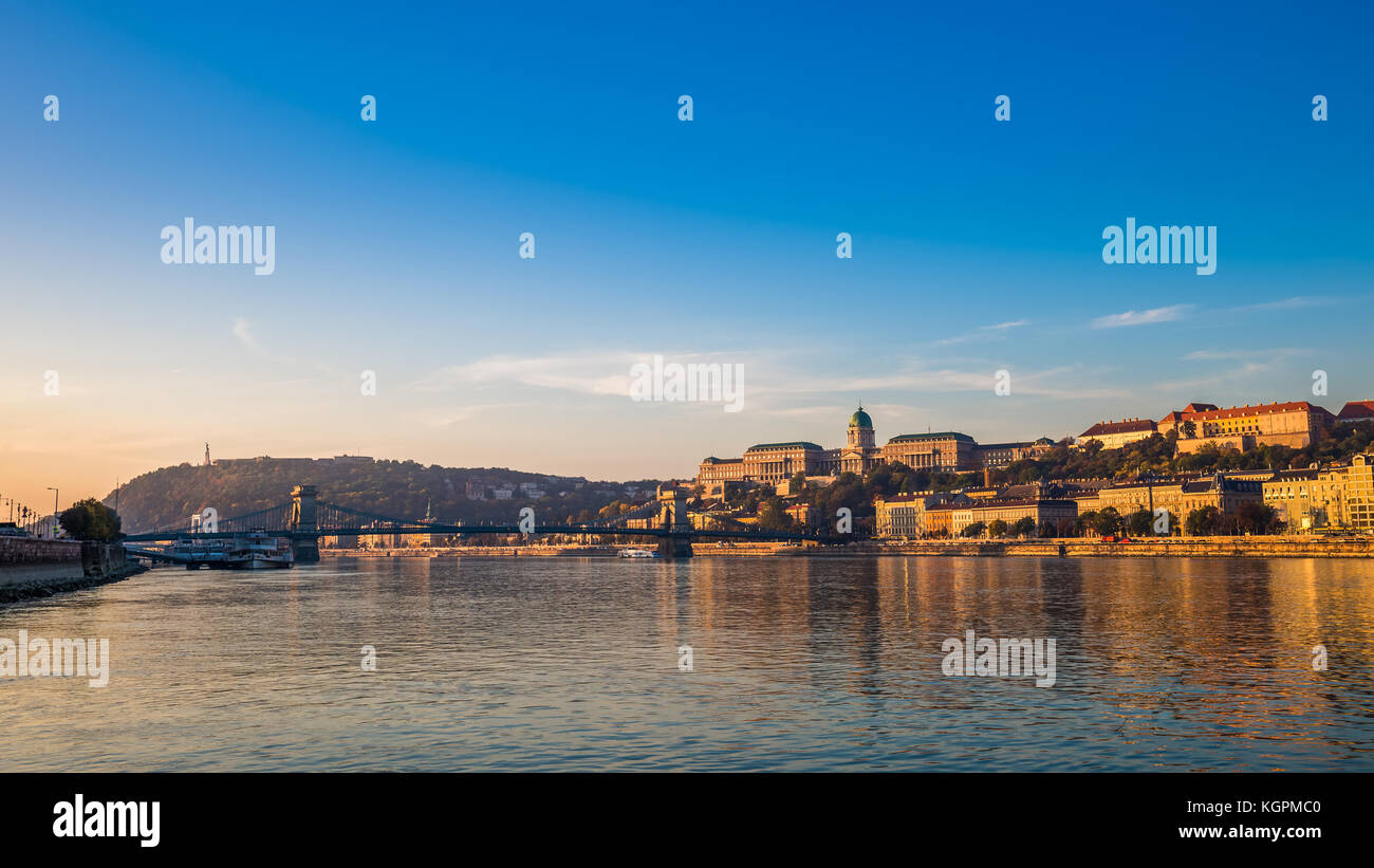 Budapest, Ungheria - la surise dorata sopra il Danubio con il Ponte delle catene Szechenyi, il Palazzo reale del Castello di Buda, la collina di Gellert e la Statua della libertà a b Foto Stock