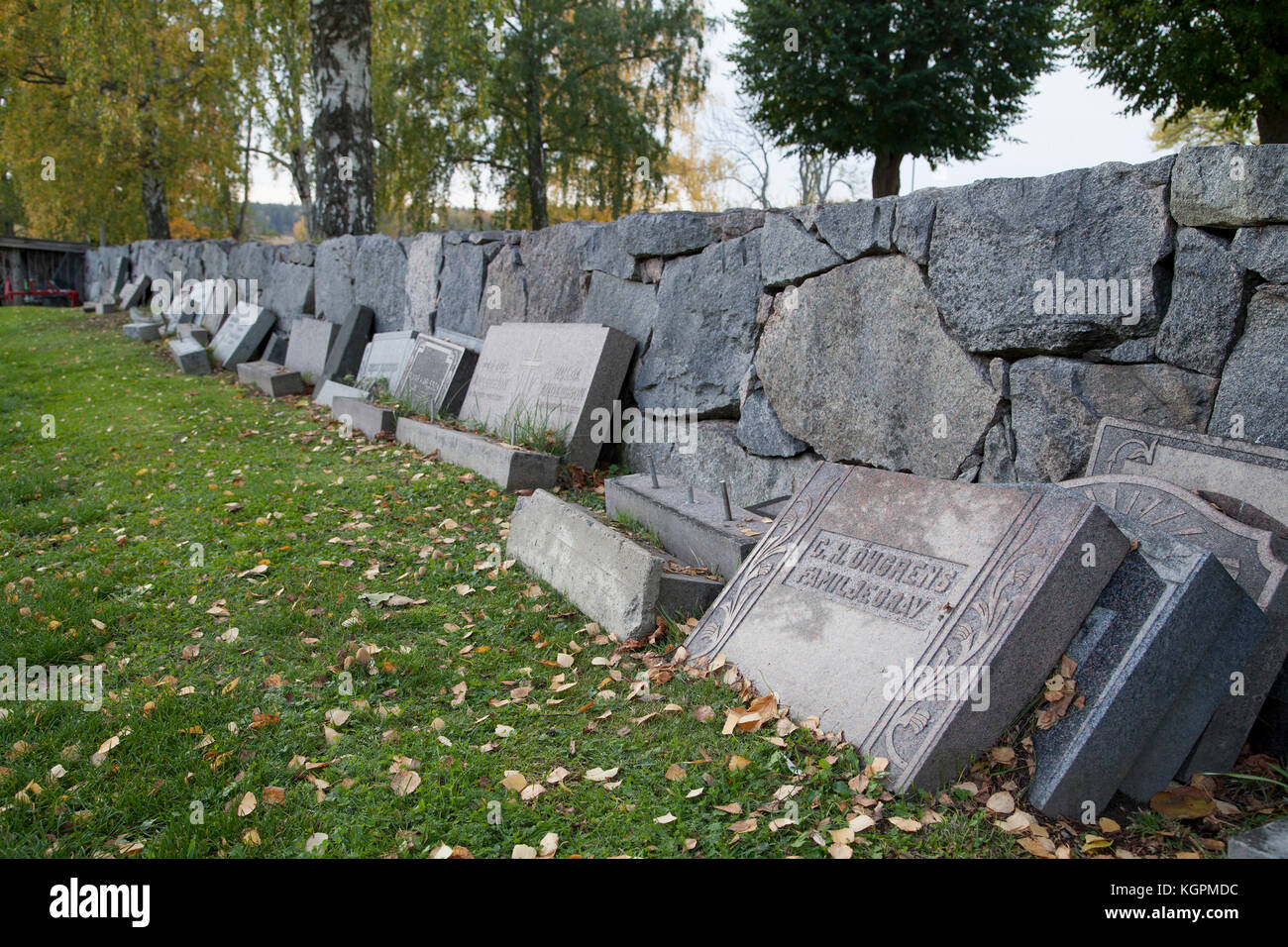 Le lapidi da completato tombe sono state fissato contro la parete di cimitero in attesa per il riutilizzo Foto Stock