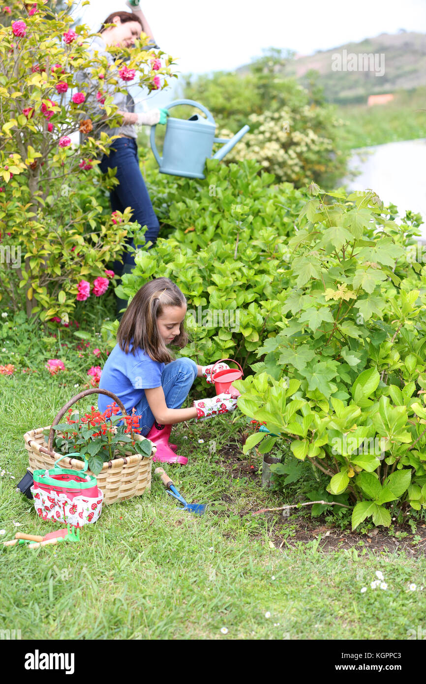 Bambina aiutando la madre a fare giardinaggio Foto Stock