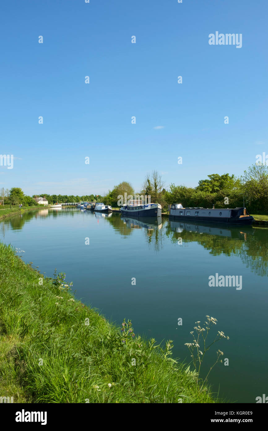 Posti barca nel porticciolo e la gente a piedi la strada alzaia del tranquillo Gloucester & Nitidezza Canal at Purton in estate il sole, Gloucestershire, Regno Unito Foto Stock