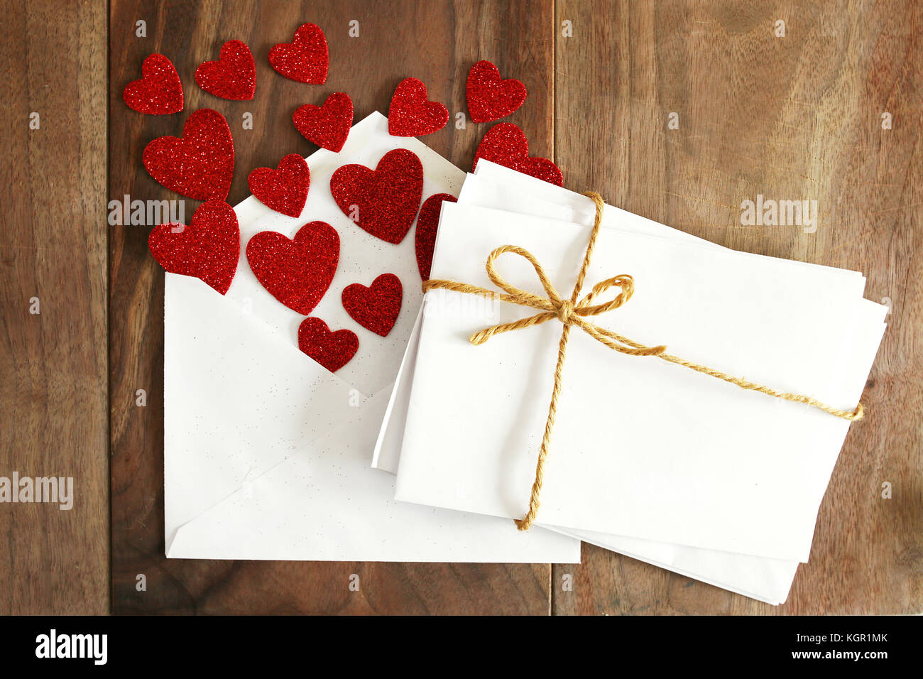 Una pila di buste vuote di legami con una stringa di spago prua, sono  accanto a un aperto il giorno di San Valentino love letter con cuori rossi  battenti fuori di esso